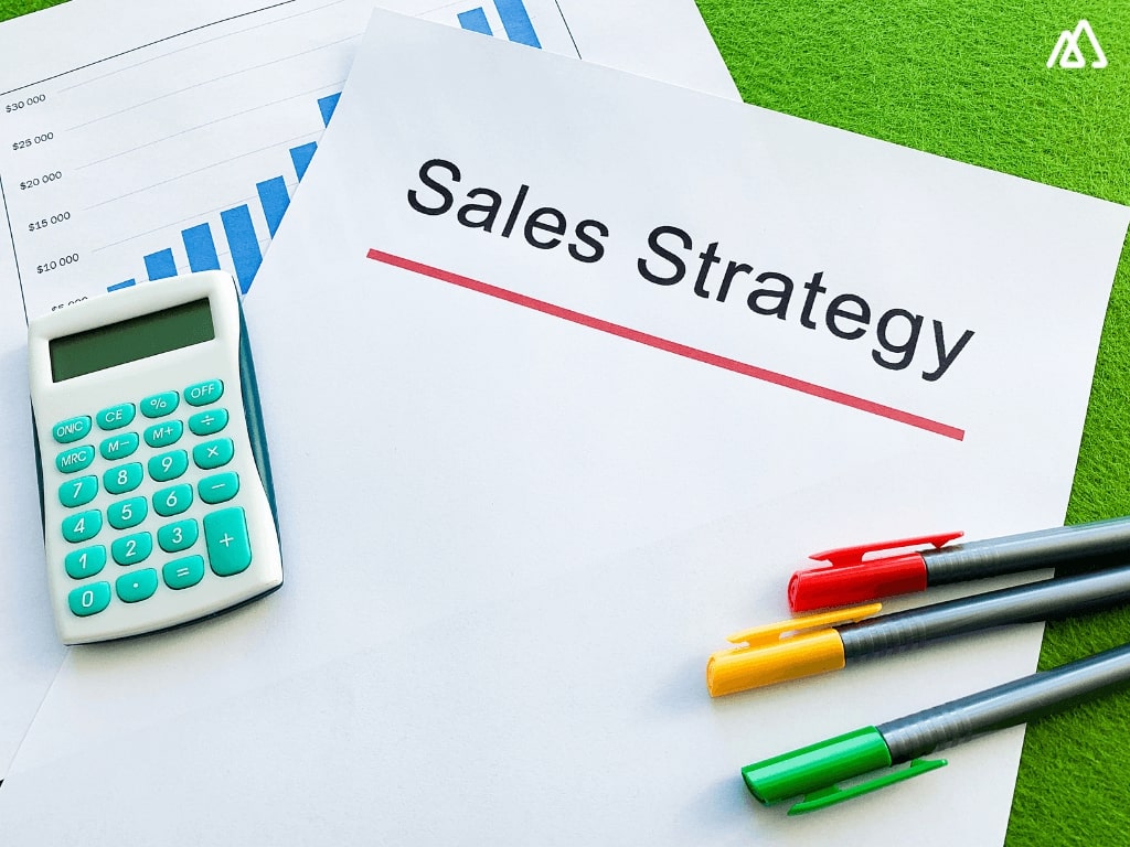 white paper with sales strategy written, with pens & calculator